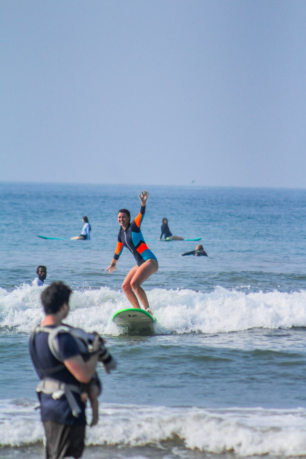 Beginner female surfer riding her first small wave in Weligama, Sri Lanka, during a surf lesson.